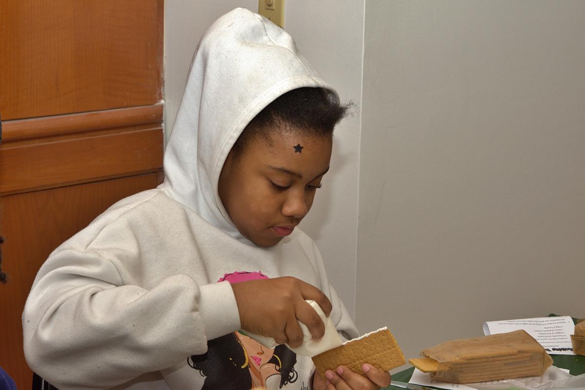 A girl building a graham cracker house