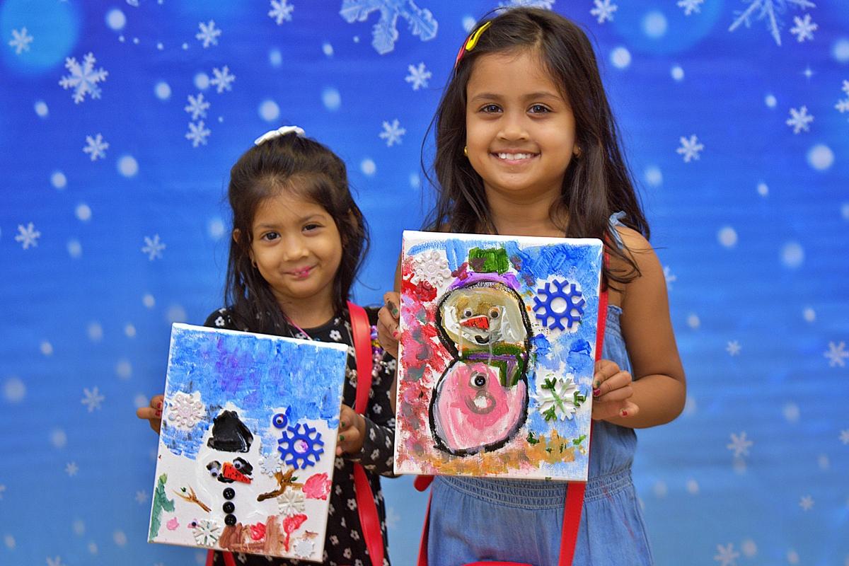 Two girls displaying snowman paintings