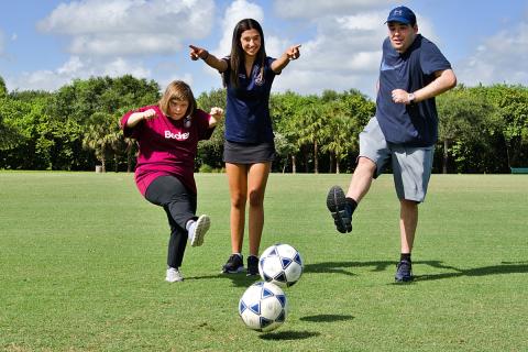 Claire McDonough shows buddies Sally Bahn and Matthew Lesser where to kick the ball.